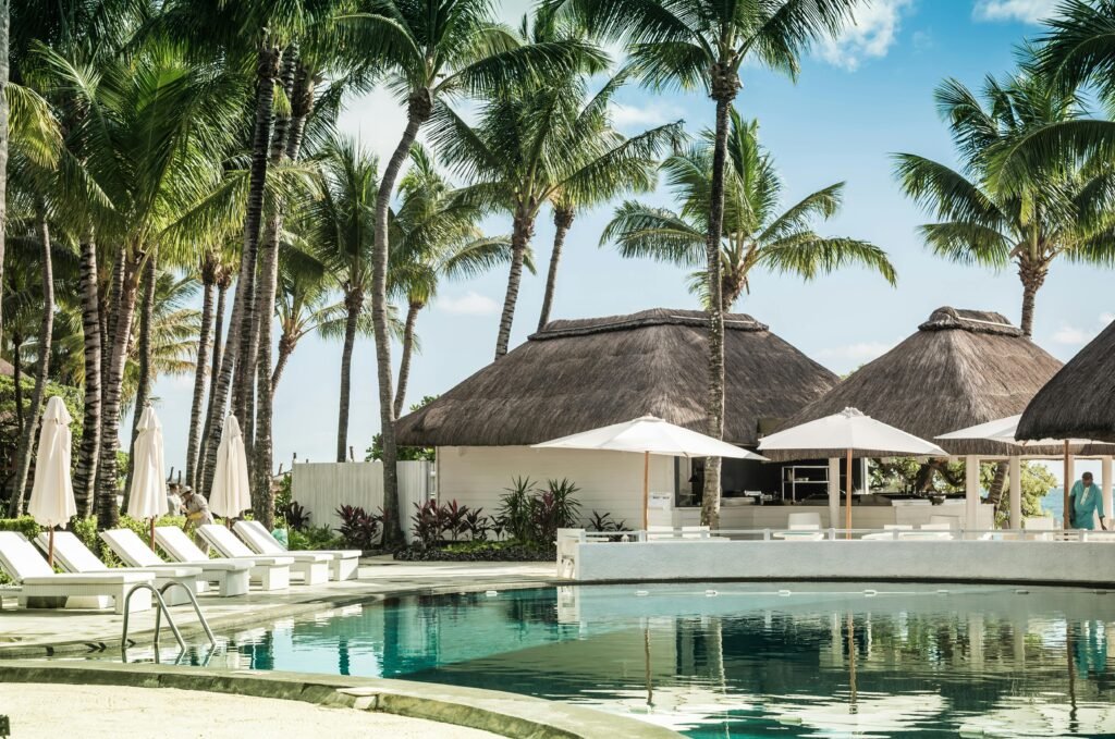 Relax by the pool at a tropical resort with palm trees and thatched huts, epitomizing a summer getaway.